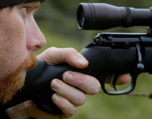 man looking through a rifle scope
