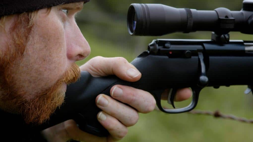 man looking through a rifle scope