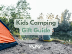 Two kids sitting by tent by river