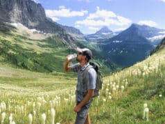 Man hiking and drinking water in mountain meadow