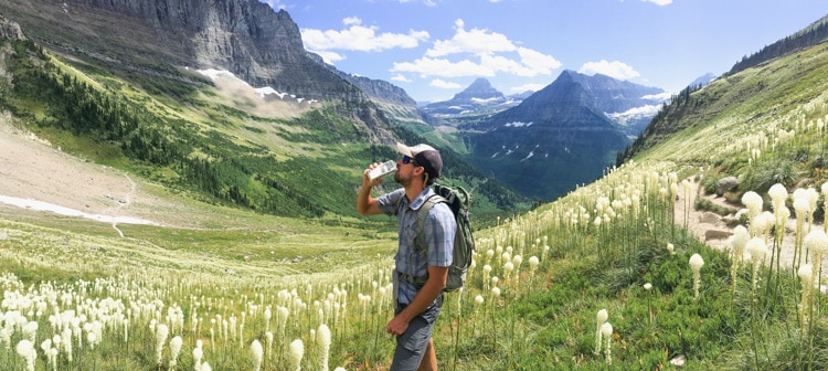Man hiking and drinking water in mountain meadow