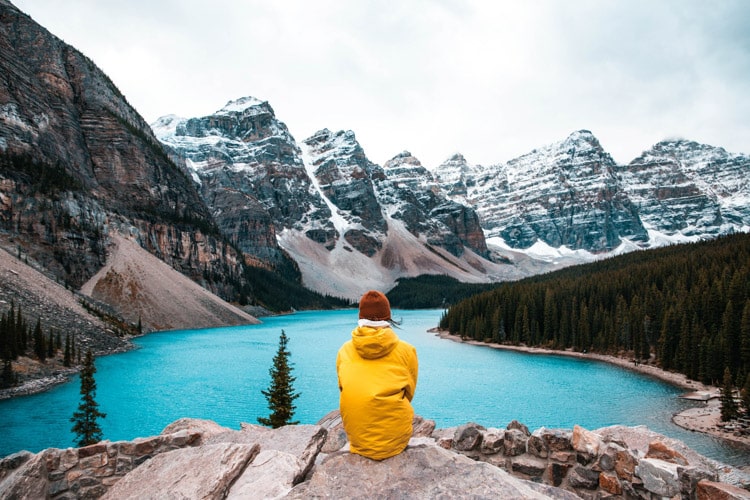 Woman sitting overlooking moraine lake and mountains