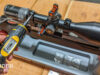 Man's hand using torque wrench to screw in rifle scope ring screws