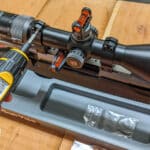 Man's hand using torque wrench to screw in rifle scope ring screws