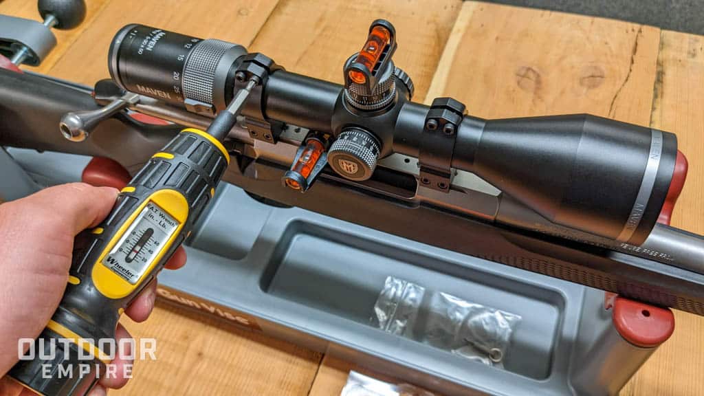 Man's hand using torque wrench to screw in rifle scope ring screws