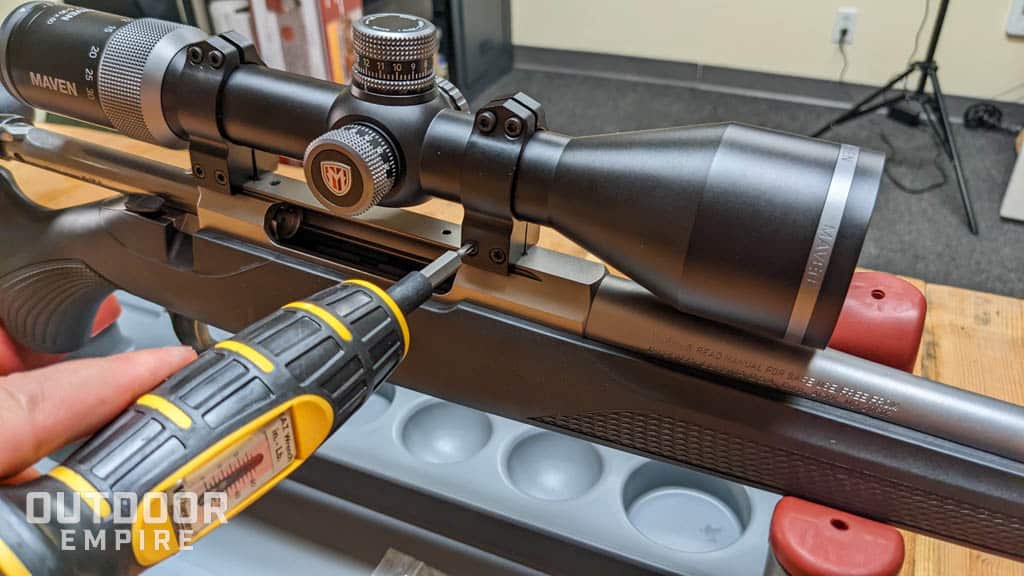 Hand using gunsmithing torque wrench to tighten scope rings on a rifle