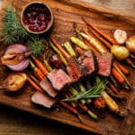 Venison steak on grilled vegetables on cutting board