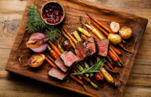 Venison steak on grilled vegetables on cutting board