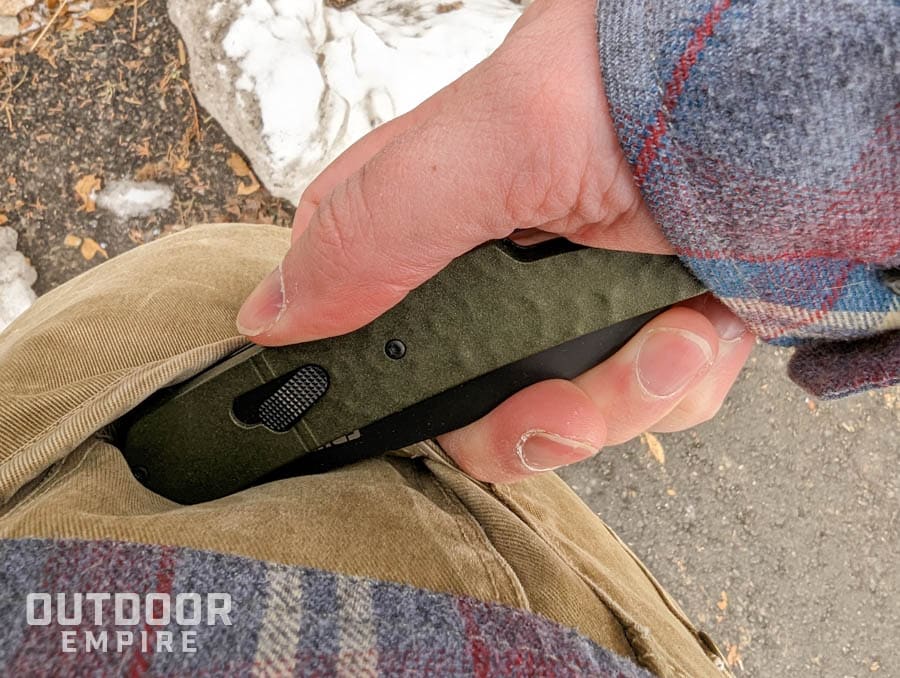 Man's hand pulling folding blade edc knife out of pants pocket