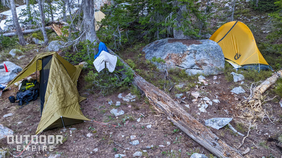 Two backpacking tents set up near each other with backpacking gear on ground