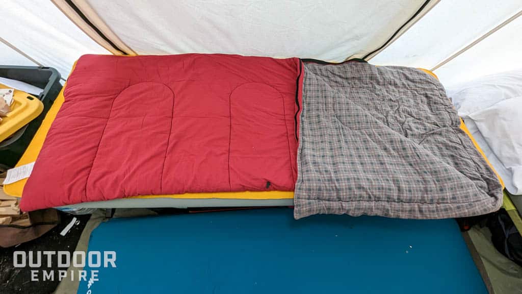Flannel sleeping bag with corner folded back in a hot tent while cold weather camping