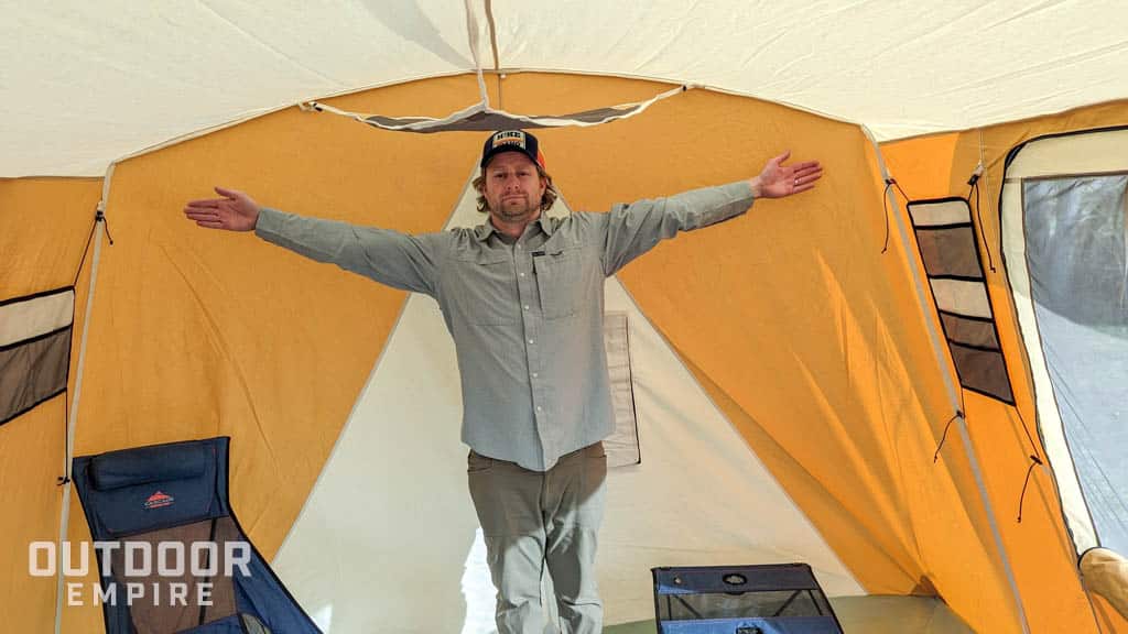 Man standing with arms out to demonstrate space inside springbar skyliner tent