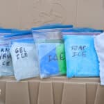 Six different homemade ice packs lined up on rim of cooler with lid open