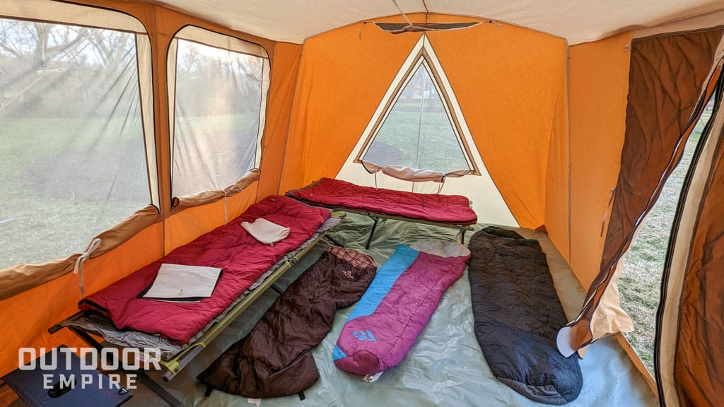 Sleeping bags and cots laid out on tent floor