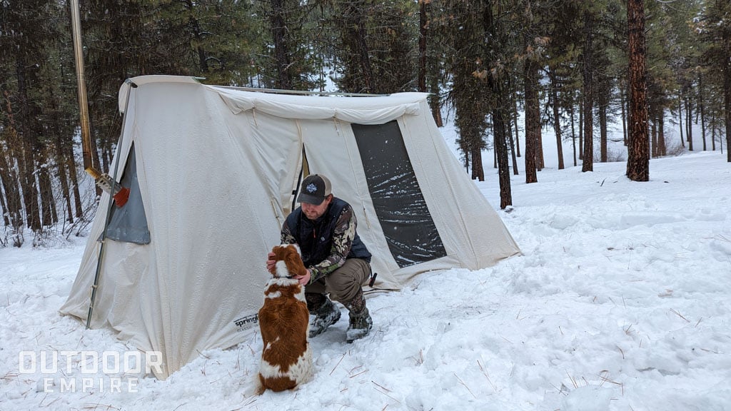 Man and dog in front of tent in the snow