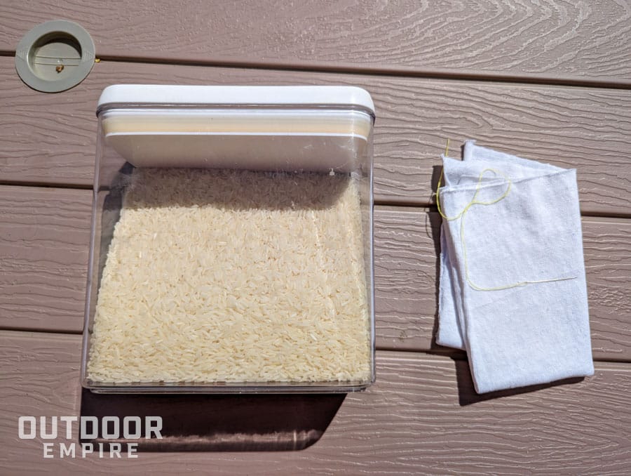 Container of rice next to a piece of cloth with a needle and thread for making a homemade ice pack