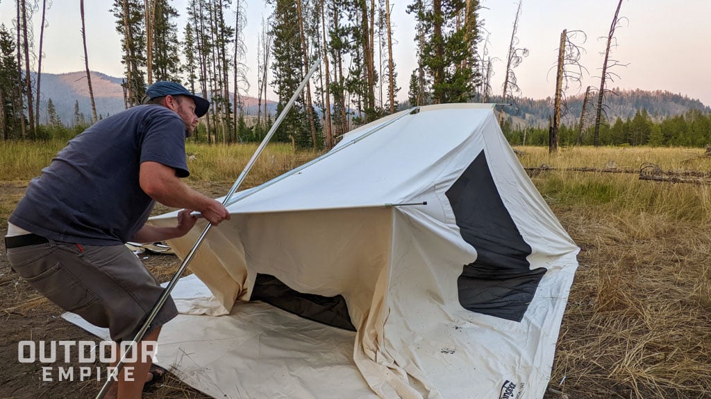 Man lifting up tent roof to insert tent pole