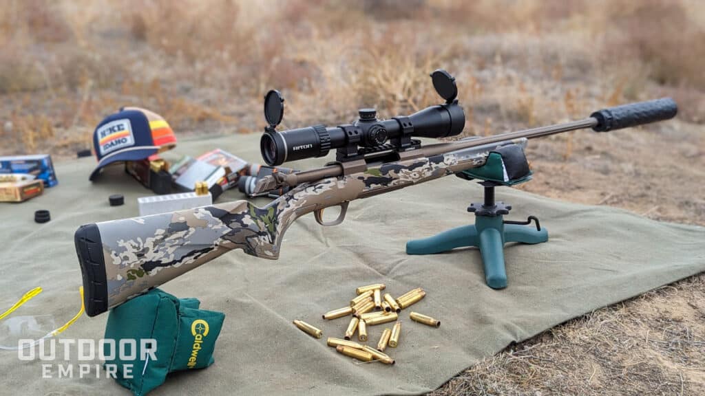 Browning x-bolt speed sr. 308 rifle with suppressor on it set up on bench rests with ammo casings next to it