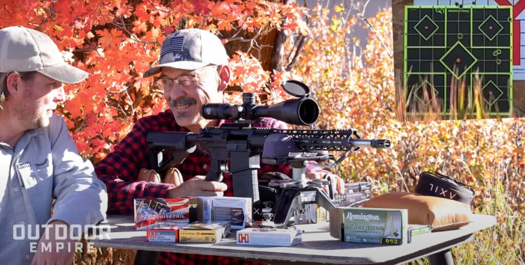 Ron spomer sitting at bench with psa pa10. 308 ar-10 rifle and laughing at chase fly