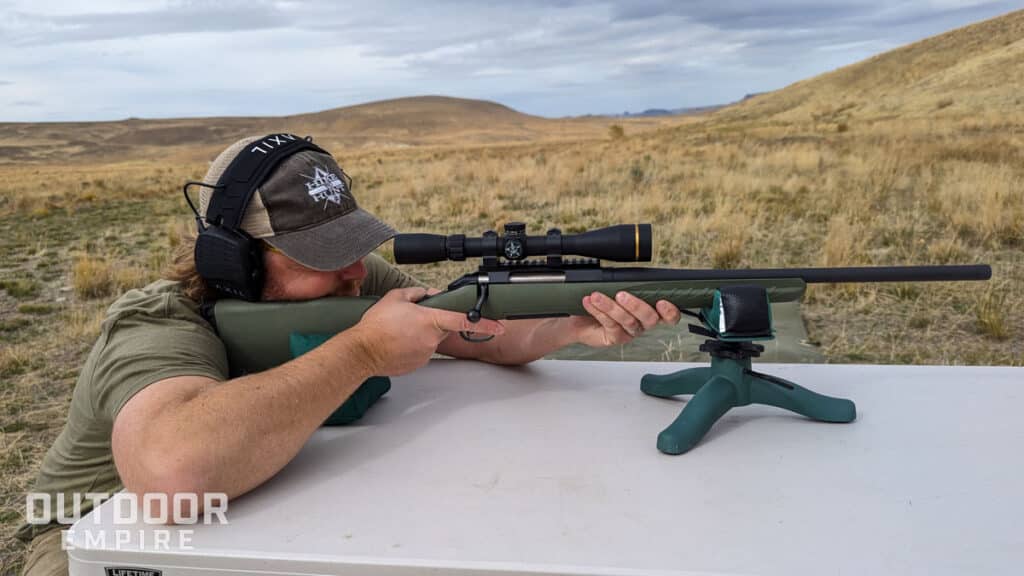 Man shooting ruger american predator. 308 rifle looking through scope on bench
