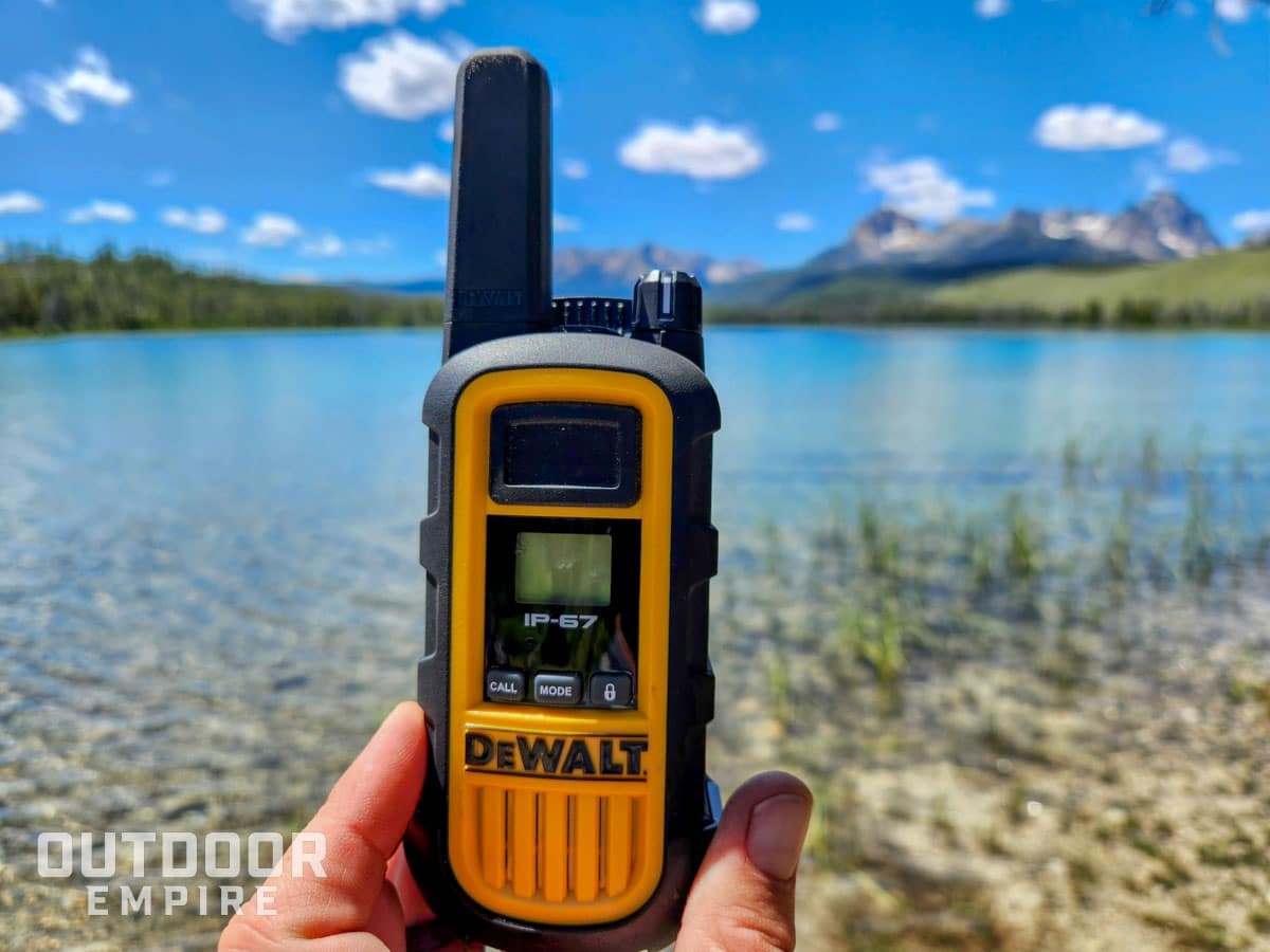 DeWalt DXFRS800 walkie talkie in hand with mountain lake in background