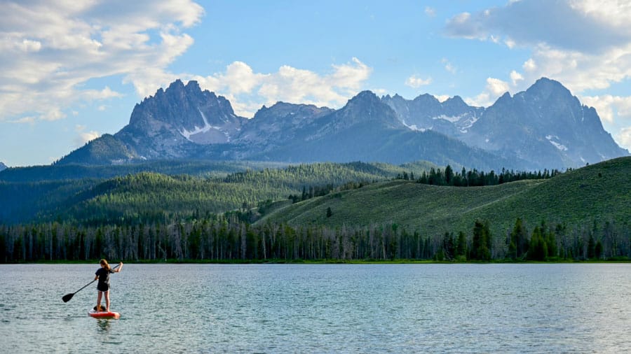Woman on a stand up paddle board with sawtooth mountains of idaho in background