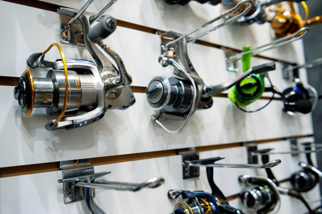 A variety of spinning fishing reels hung up on a wall