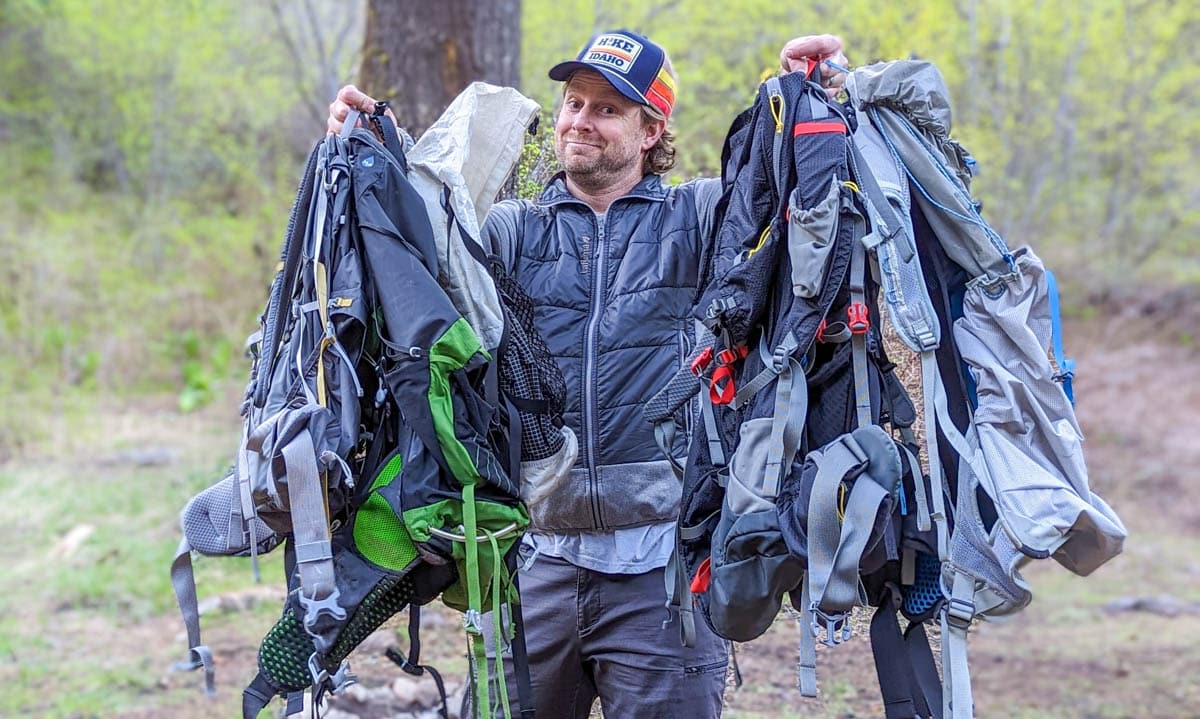 Guy holding up several hiking backpacks