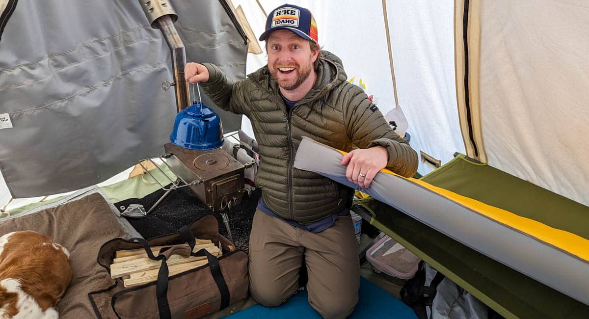 Man smiling in tent with camping gear