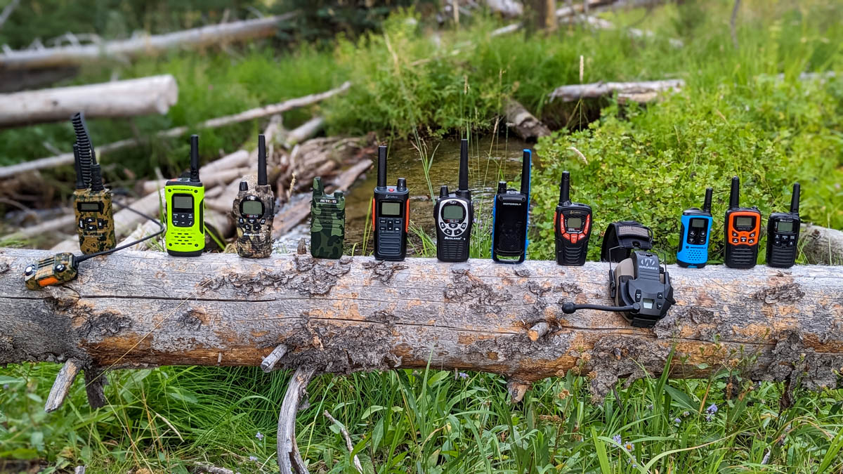 Several different walkie talkies lined up on a log