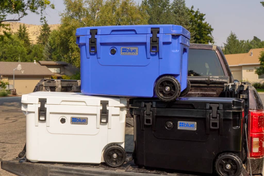 White, blue and black coolers on a truck tailgate